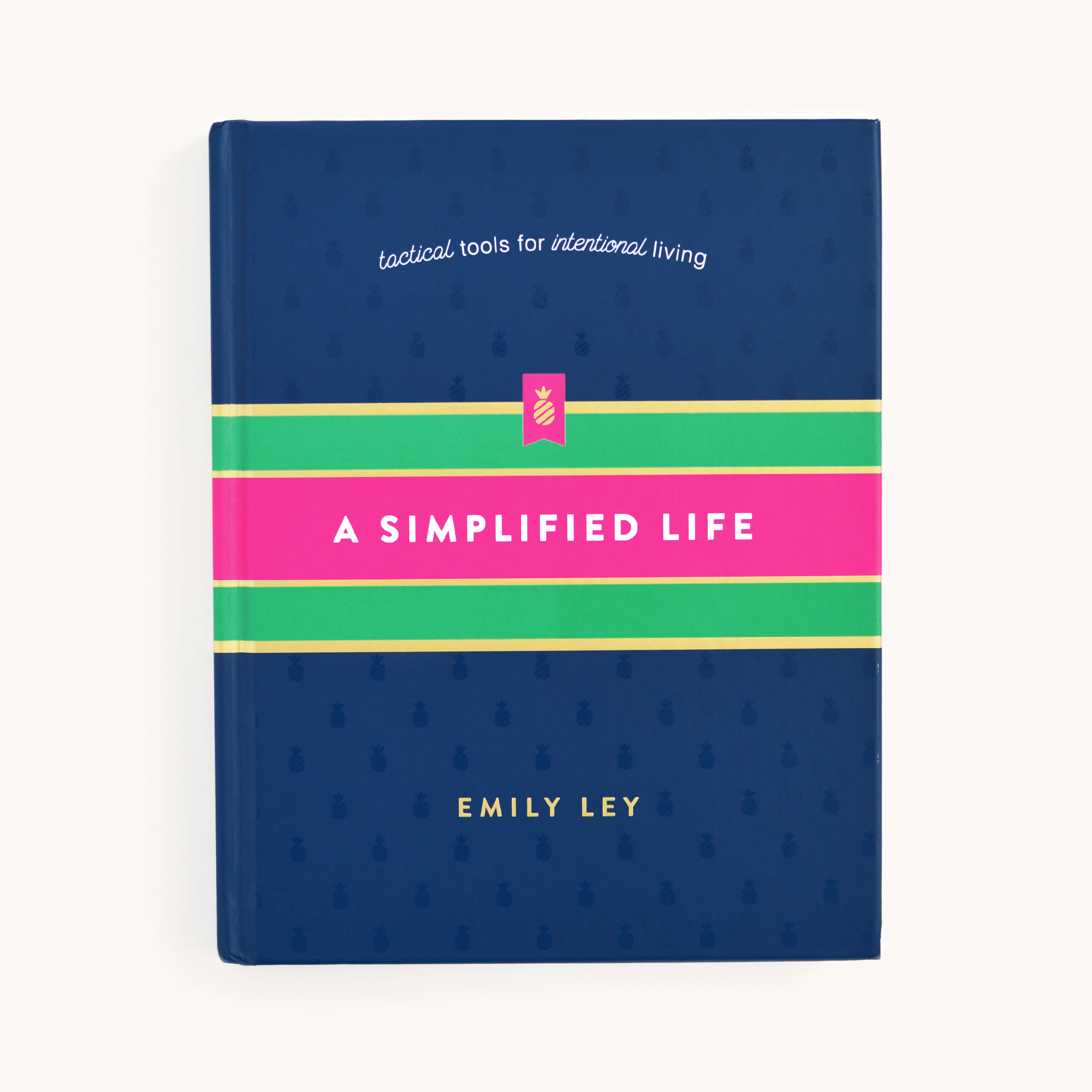 The image shows A Simplified Life by Emily Ley, from the brand Simplified. The dark blue cover features pink and green stripes, with the subtitle tactical tools for intentional living, offering tips for streamlining routines.