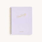 The Workbook - Hosting by Simplified is a spiral-bound guide with a white cover. It features Hosting elegantly in gold script at the center and Simplified in smaller gold letters at the bottom, offering understated sophistication for planning memorable gatherings.