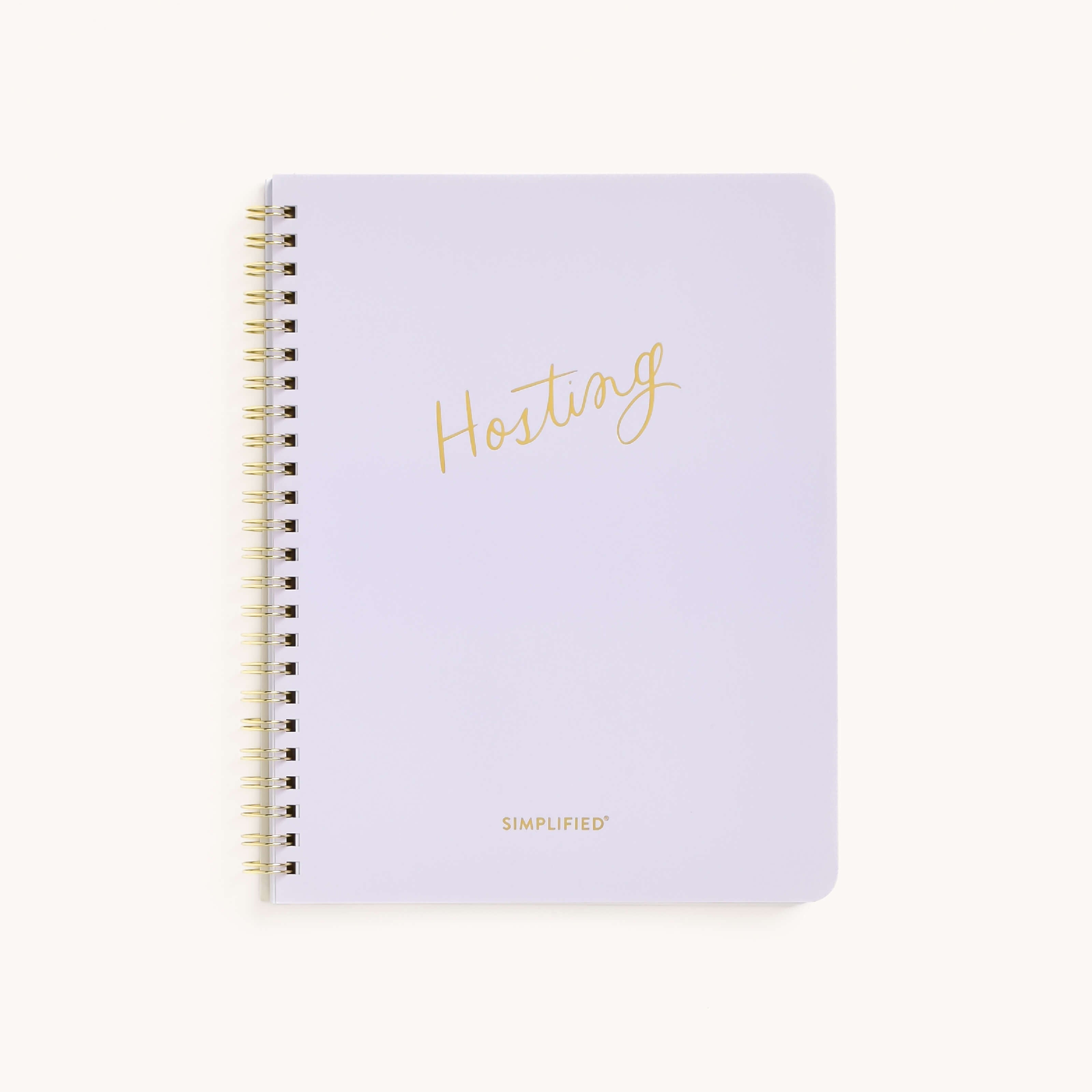 The Workbook - Hosting by Simplified is a spiral-bound guide with a white cover. It features Hosting elegantly in gold script at the center and Simplified in smaller gold letters at the bottom, offering understated sophistication for planning memorable gatherings.