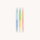 Simplified Dual-Tip Highlighter Set by Emily Ley featuring three pastel-colored highlighters in blue, green, and pink. Each highlighter includes a fine-tip marker on one end and a chisel-tip highlighter on the other.