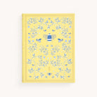 The Linen Journal - Yellow by Simplified showcases a yellow cover adorned with a large bee, smaller bees, and detailed blue vine patterns with leaves and flowers, inviting creativity and reflection. Ideal for journal enthusiasts.