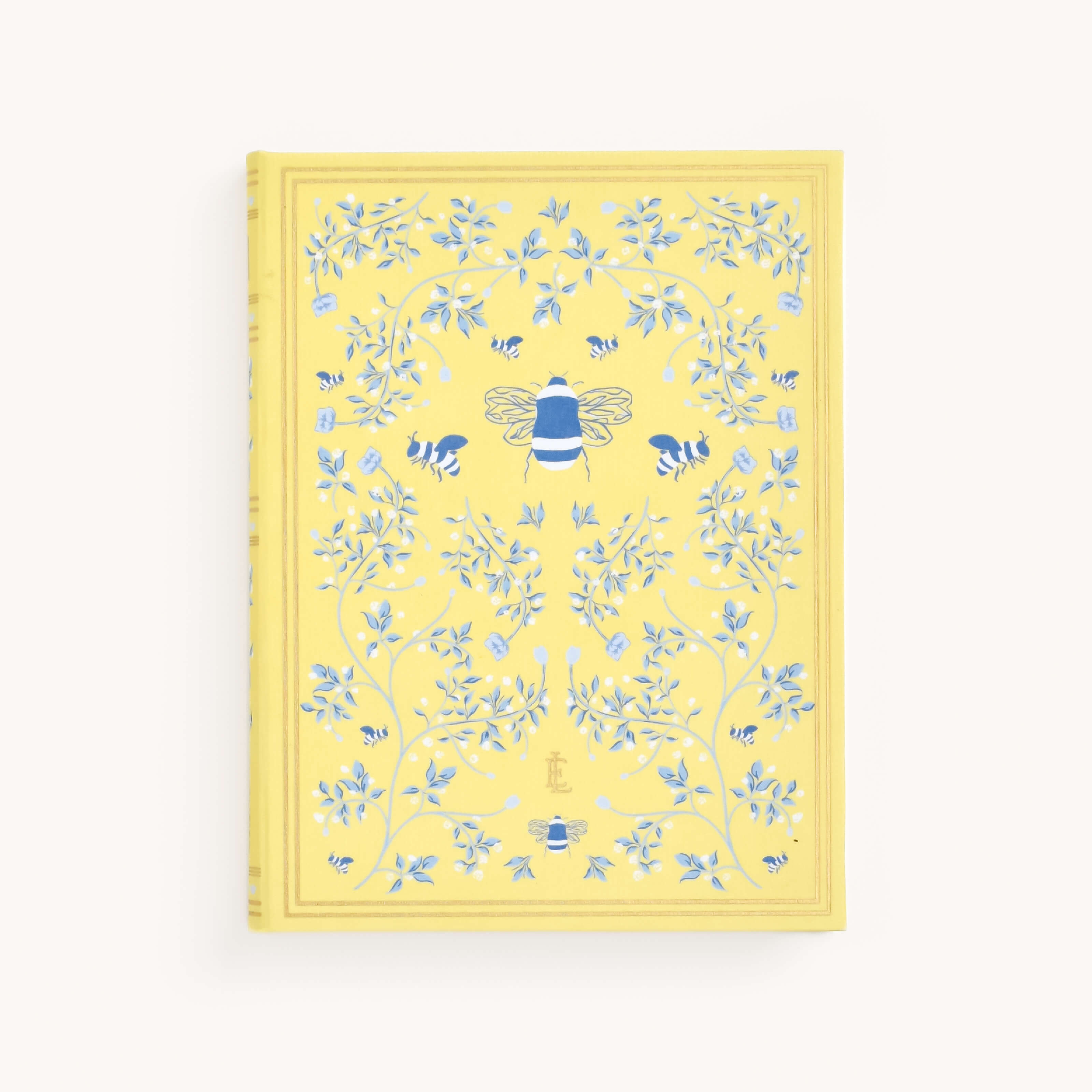 The Linen Journal - Yellow by Simplified showcases a yellow cover adorned with a large bee, smaller bees, and detailed blue vine patterns with leaves and flowers, inviting creativity and reflection. Ideal for journal enthusiasts.