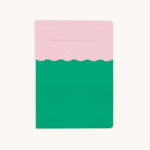 The Simplified Mid-Size Notebook - Less Chasing More Cherishing features an elegant cover with a pink top, green bottom, and wavy divider. The words LESS CHASING, MORE CHERISHING adorn the pink section. It has a plain white background and saddle-stitched binding.