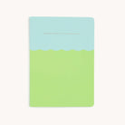 Simplifieds Mid-Size Notebook - Magic In The Ordinary features a stylish pastel green and light blue wavy cover with durable saddle-stitched binding and elegant gold text, There is magic in the ordinary.