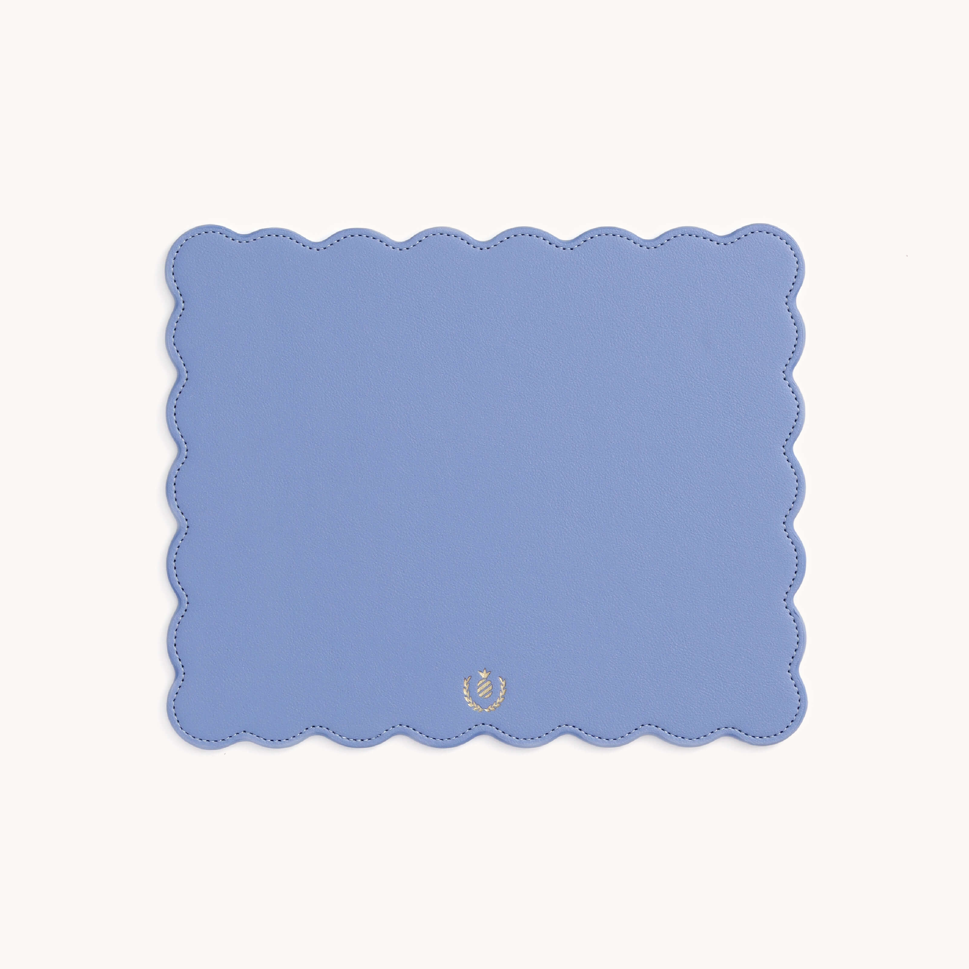 The Simplified Scalloped Mousepad is a rectangular leatherette pad in light blue with scalloped edges and a small gold emblem near the bottom, making it a stylish desk accessory.