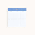 The Notepad - Grocery List by Simplified is a charming blue and white pad with columns for Produce, Deli, Pantry, Frozen, Dairy, and Miscellaneous. It features a small decorative emblem to keep your reminders organized and easily accessible.