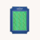 Simplified Arrow Paper Clips Set by Emily Ley featuring 12 gold arrow-shaped paper clips, packaged on a green backing with a navy frame.