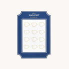 Simplified Coffee Cup Paper Clips Set by Emily Ley featuring 12 gold mug-shaped paper clips, packaged on a white backing with a navy frame.