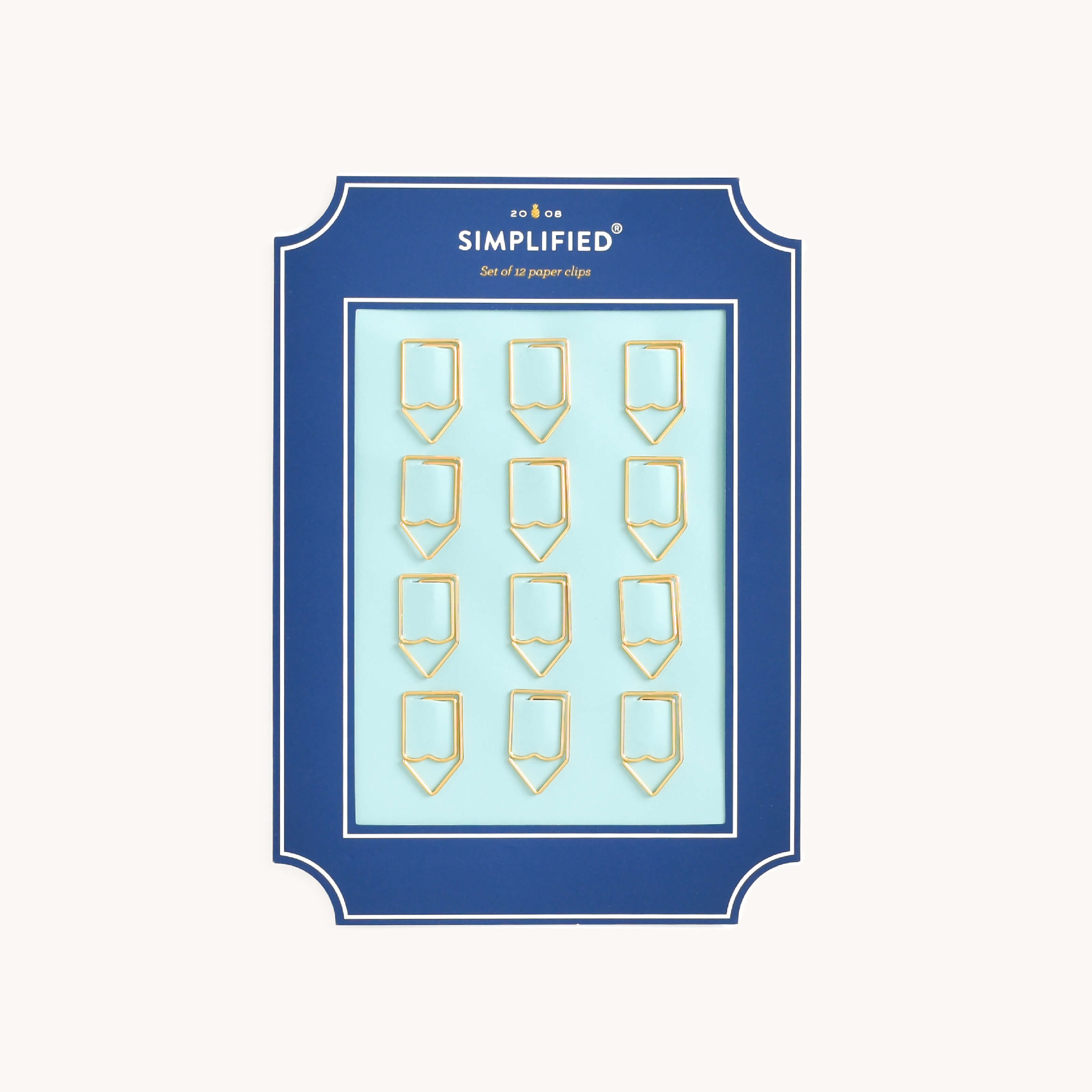 Simplified Pencil Paper Clips Set by Emily Ley featuring 12 gold pencil-shaped paper clips, packaged on a light blue backing with a navy frame.