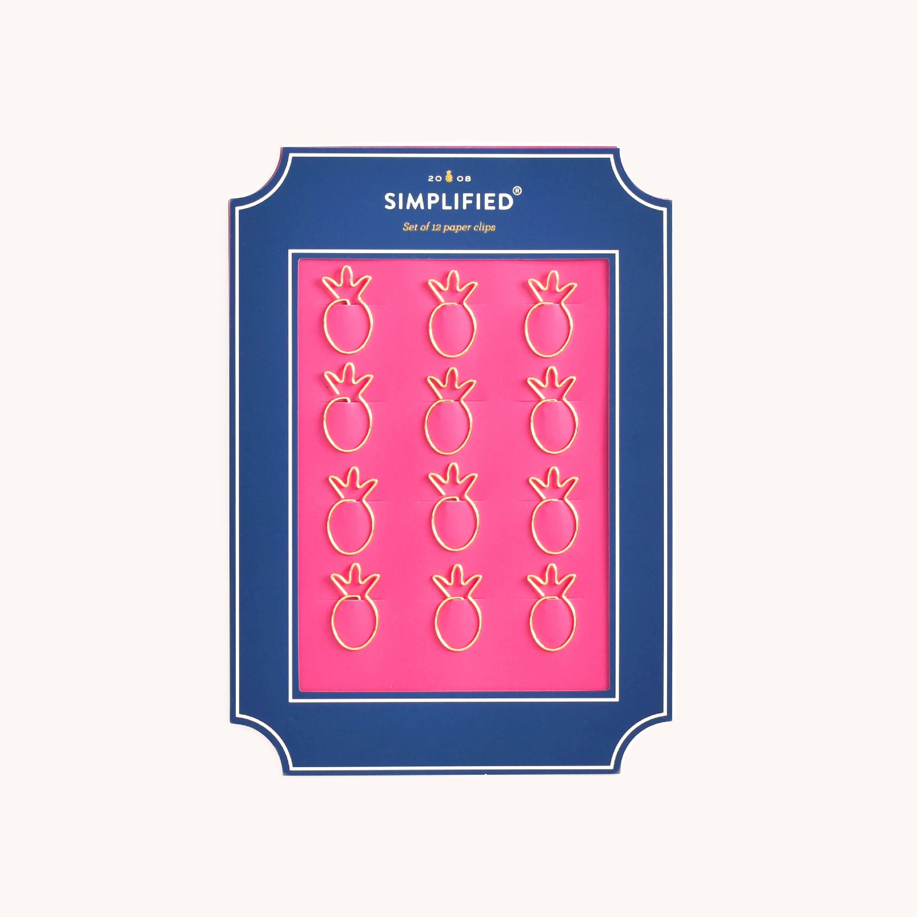 Simplified Pineapple Paper Clips Set by Emily Ley featuring 12 gold pineapple-shaped paper clips, packaged on a pink backing with a navy frame.