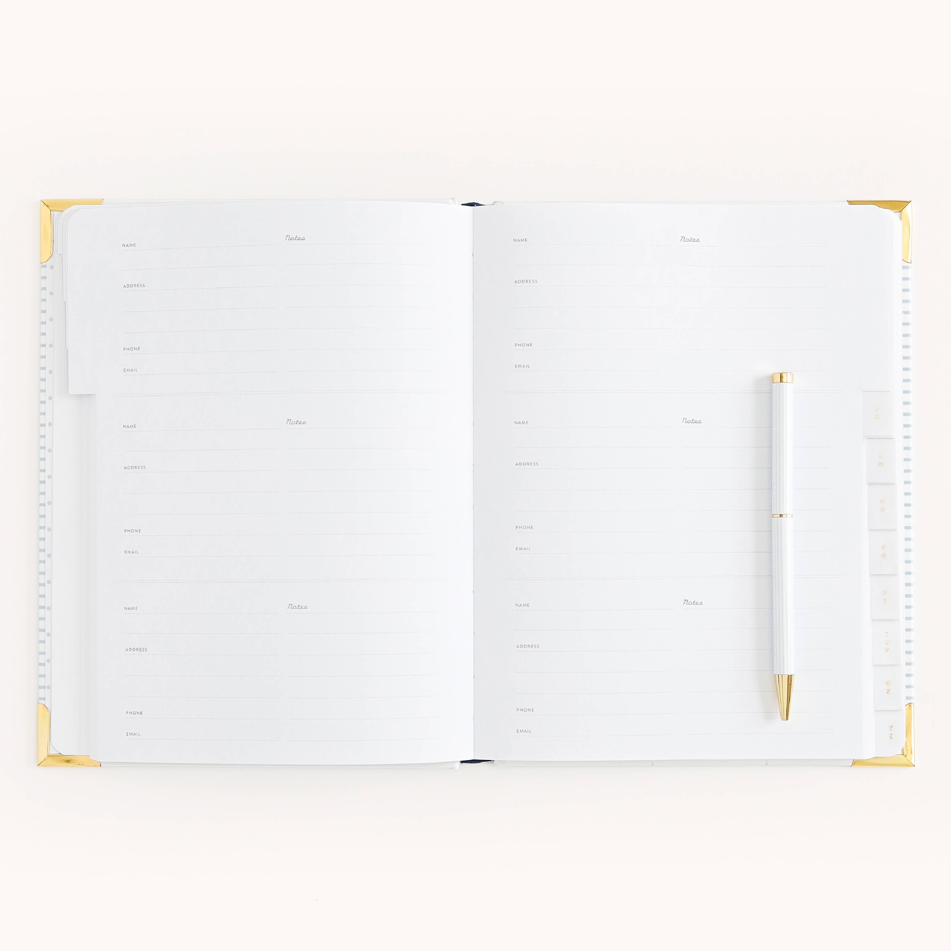 The Simplified Address Book features lined pages, gold-accented corners, and sections for each week with Monday through Sunday. A white pen with gold details sits on the right page, perfect for noting contact details. The backdrop is a soft off-white.