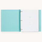 The open Simplified Baby Book - Mint, with a light blue polka dot cover and metal rings, features guided spaces on white pages to document details like name, birthdate, and doctor. Expand memories with customizable page packs in this delightful baby book.