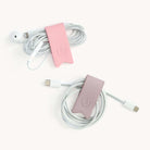 Two sets of earbuds and charging cables are neatly wrapped with Simplifieds Cord Organizers in Blush & Lilac on a white background, effortlessly eliminating cable clutter.