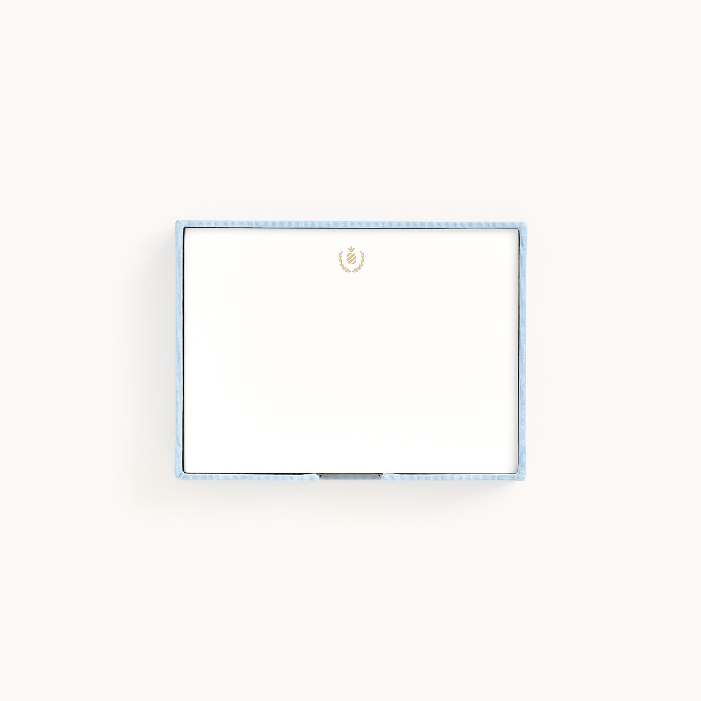 The Desk Jotter - Carolina Linen by Simplified is a closed rectangular box in light blue with a gold embossed emblem on top, set against a plain white background.