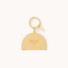 The Rainbow Key Chain by Simplified features a gold enamel half-circle pendant inscribed with THE JOY IS IN THE JOURNEY, making it an elegant and practical everyday essential, complemented by a small tag on the ring, all set against a plain white background.