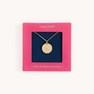 The Grace Not Perfection gold necklace from Simplified exudes elegance with its circular pendant. Its presented in a pink gift box with a dark blue interior, adorned with SIMPLIFIED and GRACE, NOT PERFECTION NECKLACE.