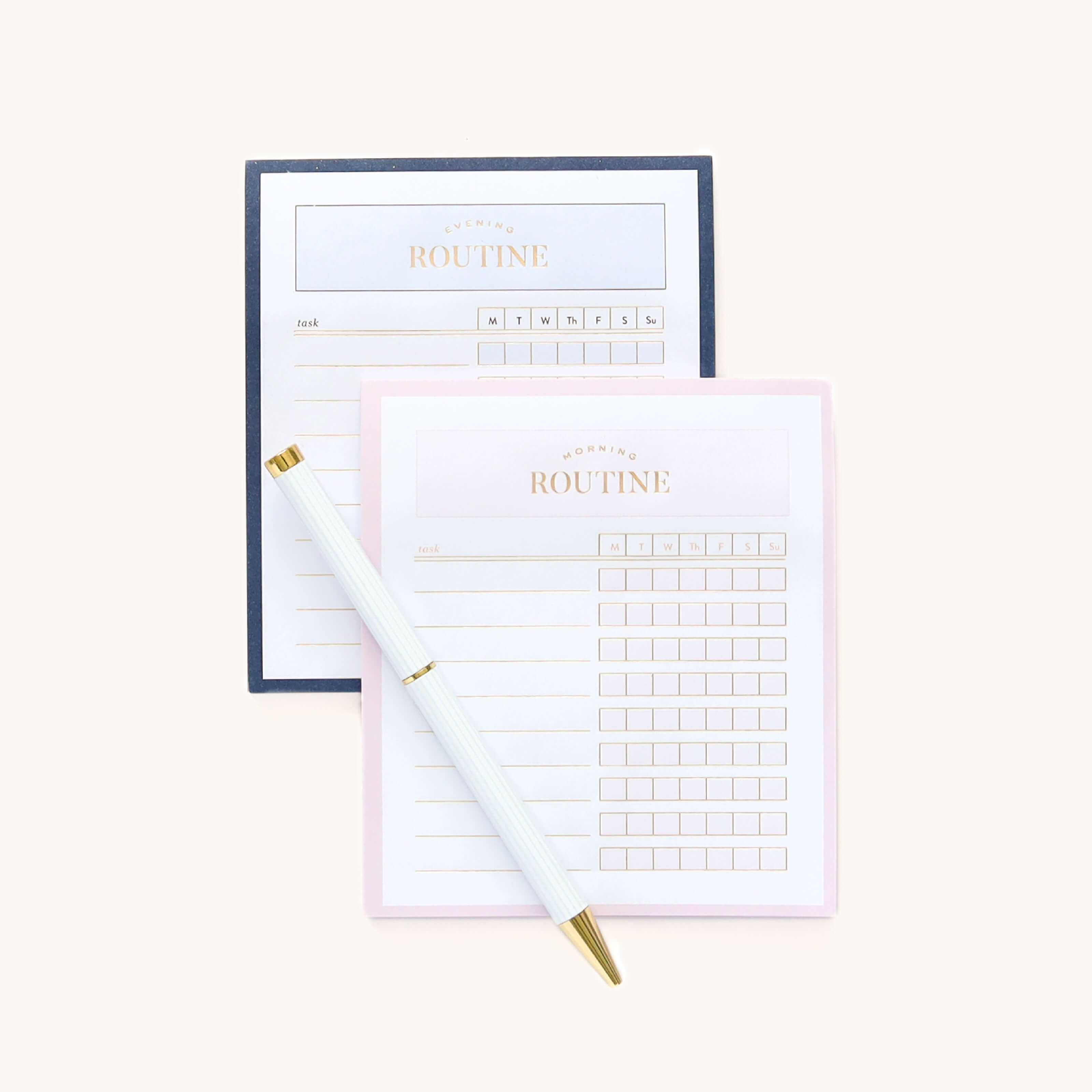 The Sticky Note Set - Routines by Simplified includes two planner sheets, one blue-bordered and the other pink, with sections for tasks and weekly planning. A white and gold pen is diagonally placed across the sheets, ideal for reminders or grocery lists.