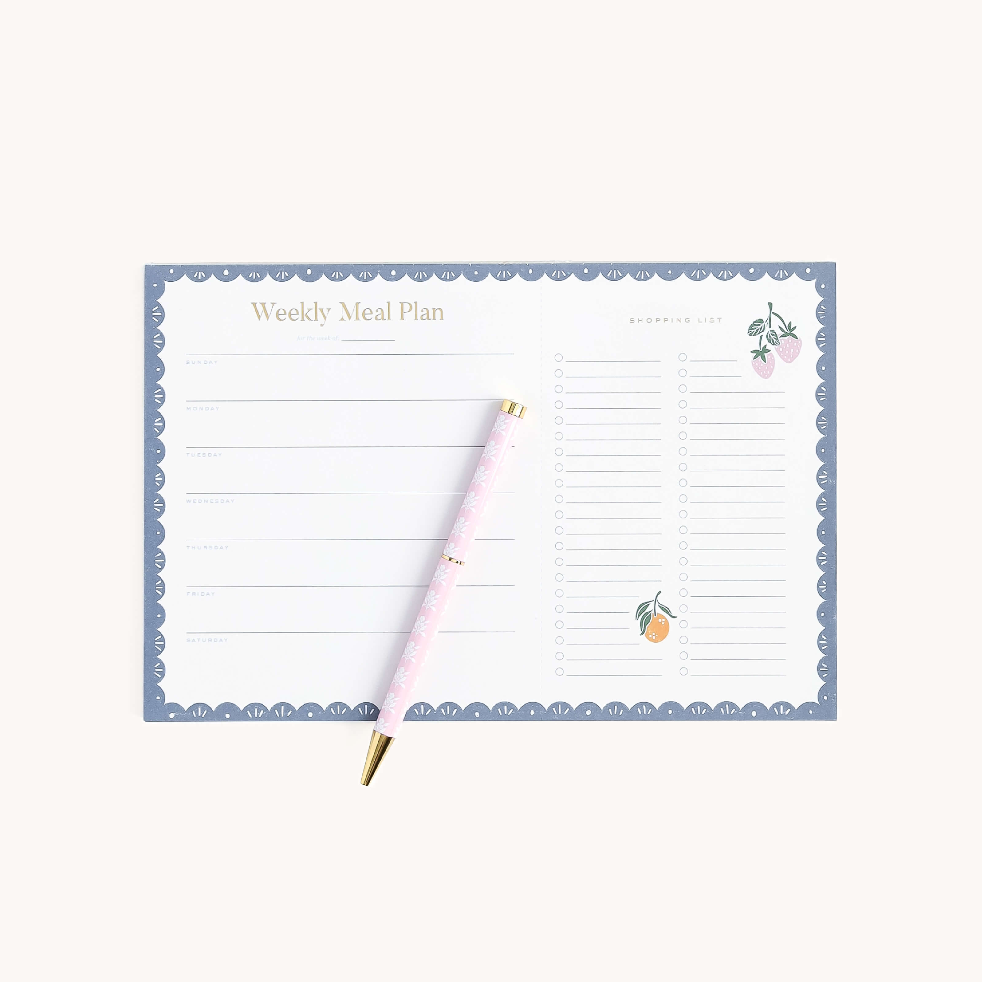 The Simplified Meal Planning Notepad features sections for daily meals and a grocery list, adorned with a scalloped blue border and fruit illustrations. A pink and gold pen is included for your planning needs.