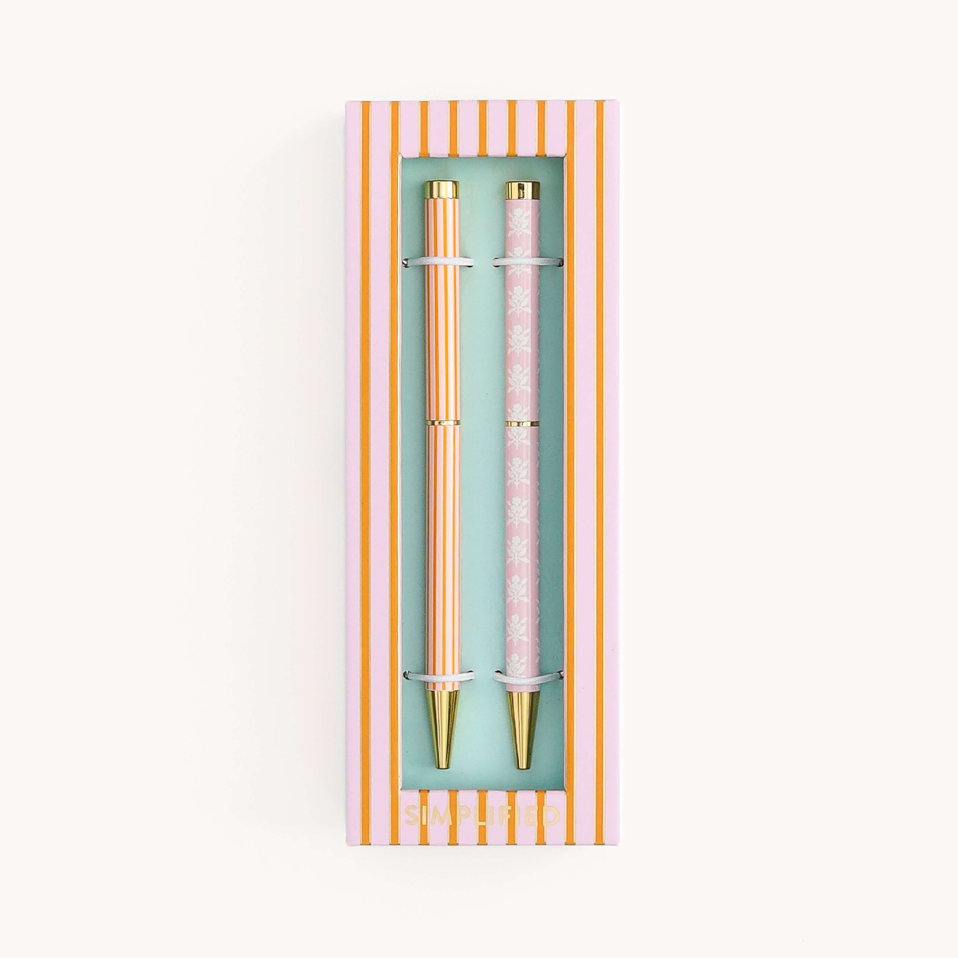 Simplified by Emily Ley | Twist Pen Set featuring two metal pens in Cabana Pinstripe and Blush Block designs, shown in a ivory two-piece box with a clear view window.