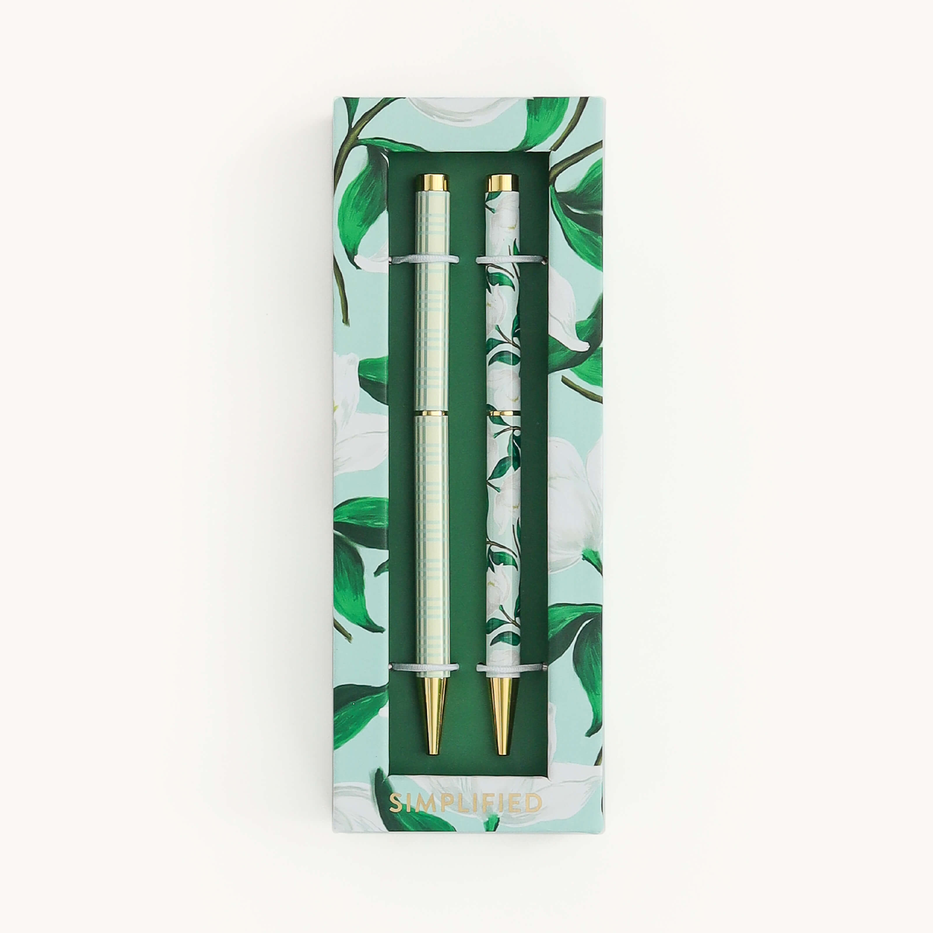 Simplified by Emily Ley | Twist Pen Set featuring two metal pens in Savannah Blooms and Pistachio Plaid designs, shown in a ivory two-piece box with a clear view window.