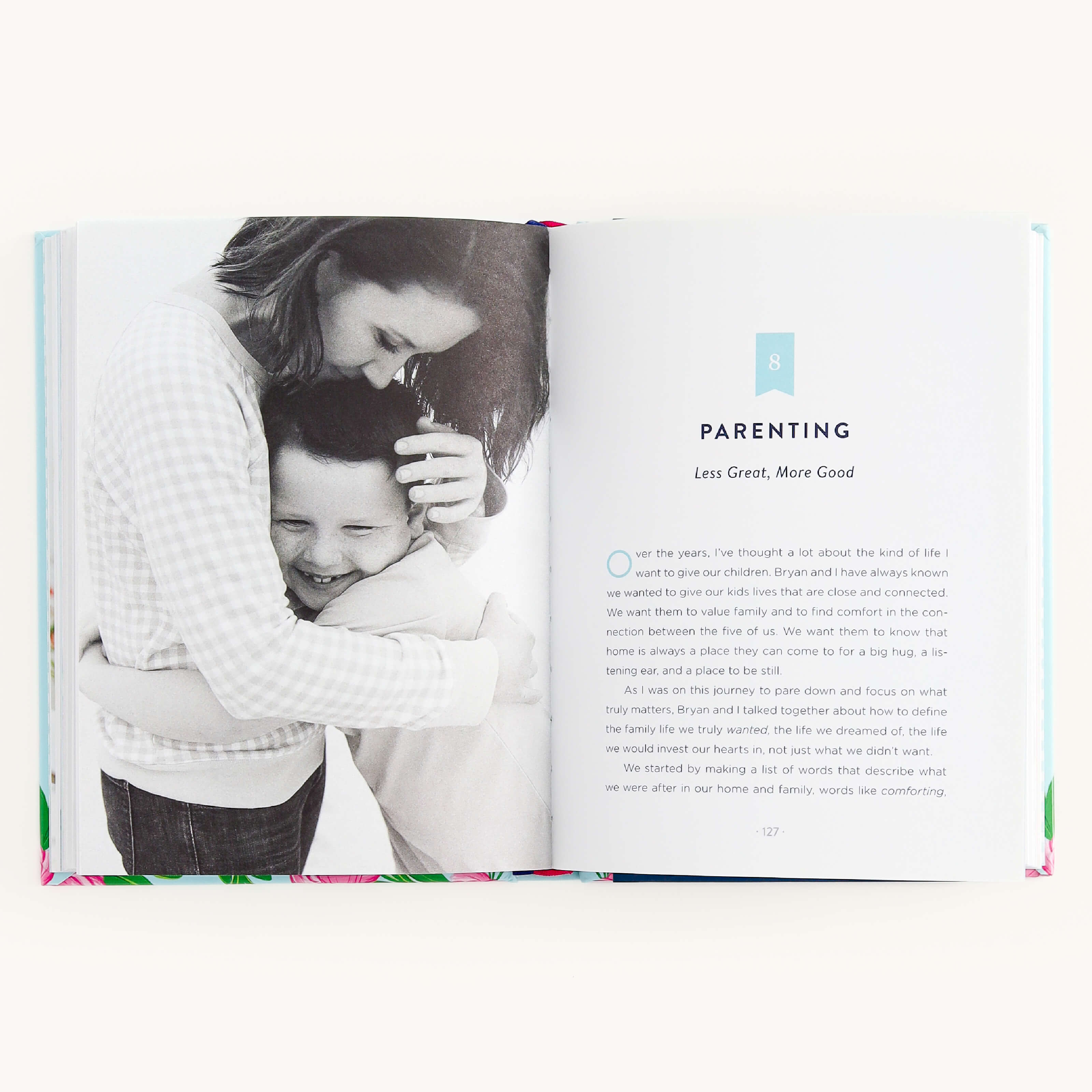 In the book When Less Becomes More by Emily Ley, an open chapter titled Parenting: Less Great, More Good includes a heartwarming black-and-white photo of a person hugging a child and text with a drop cap O, embodying thoughtful living.