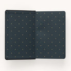 Open Simplifieds 2024-2025 Daily Dapperdesk Planner in a Black Tie color with a leatherette cover and small gold dot pattern on the inside, ideal for your 12-month planner, set against a light gray background.