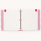 An open binder adorned with pink and white paper and a small red anchor pattern, similar to the Simplified Big Kid Book - Raspberry. Pink tabs peek from the edges, and red bookmarks highlight adventures. The binder rings are partly visible in the center.