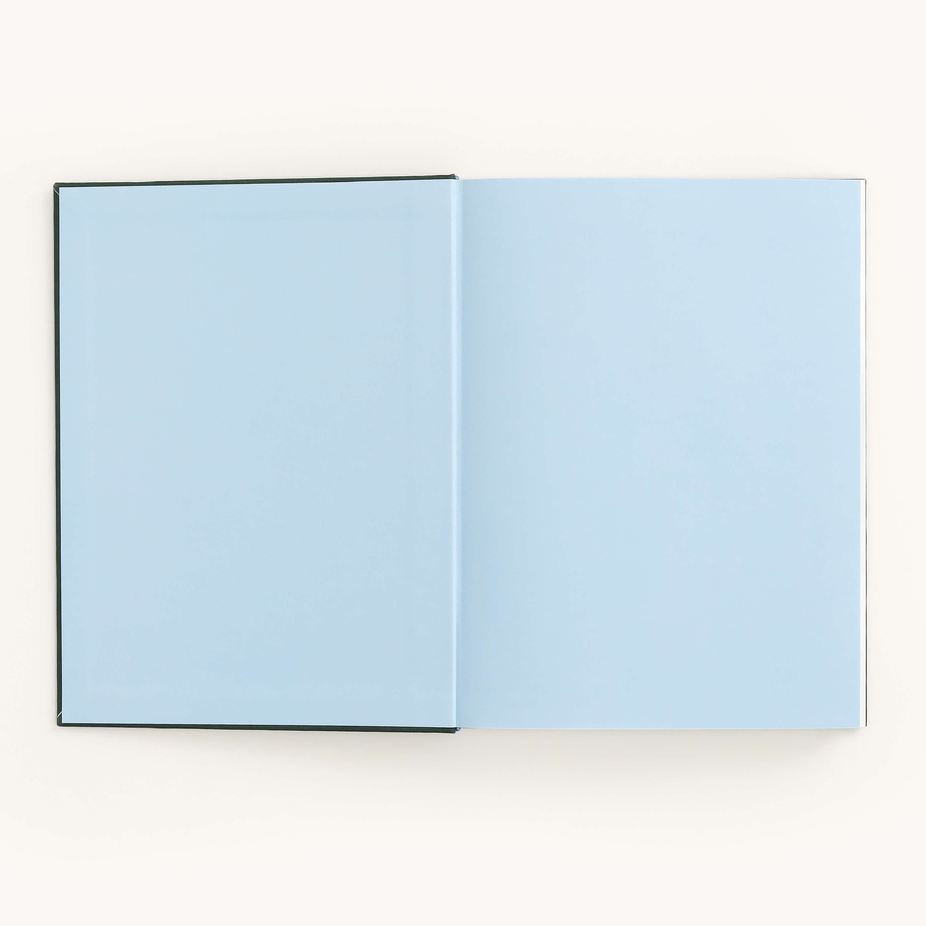 The Grace Linen Journal by Simplified elegantly displays blank, light blue pages on a plain white background. Its linen hardcover enhances the serene design, providing an ideal space for your thoughts and dreams.