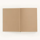 A Simplified Linen Journal - Gratitude with blank tan pages lies open on a white surface, its linen hardcover gently supporting the spine to enhance its simple, minimalistic charm.