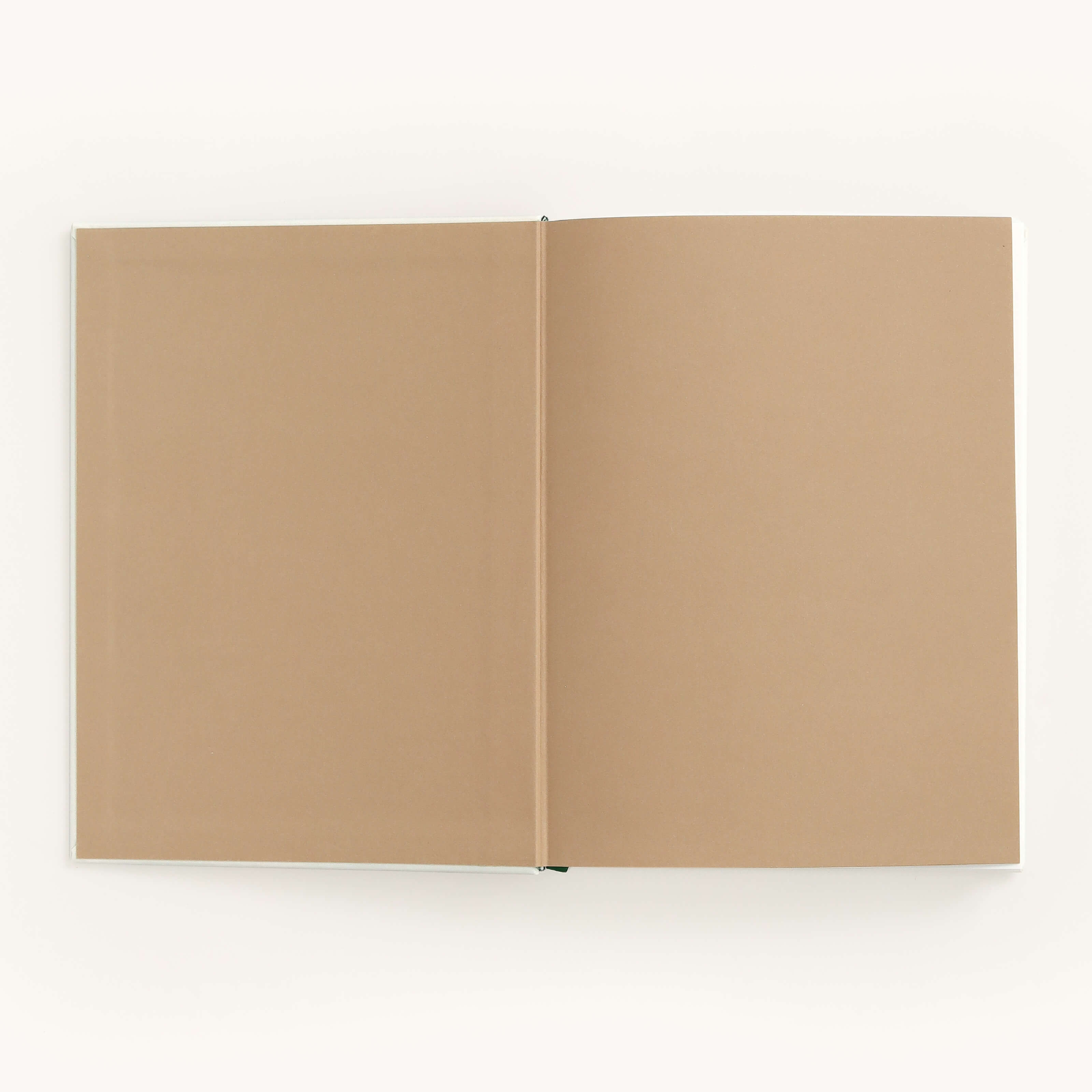 A Simplified Linen Journal - Gratitude with blank tan pages lies open on a white surface, its linen hardcover gently supporting the spine to enhance its simple, minimalistic charm.