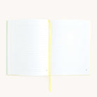 A Linen Journal - Yellow by Simplified, with lined pages and a yellow ribbon bookmark, rests open in the center. Its laid flat on a plain white background, inviting creativity and reflection.