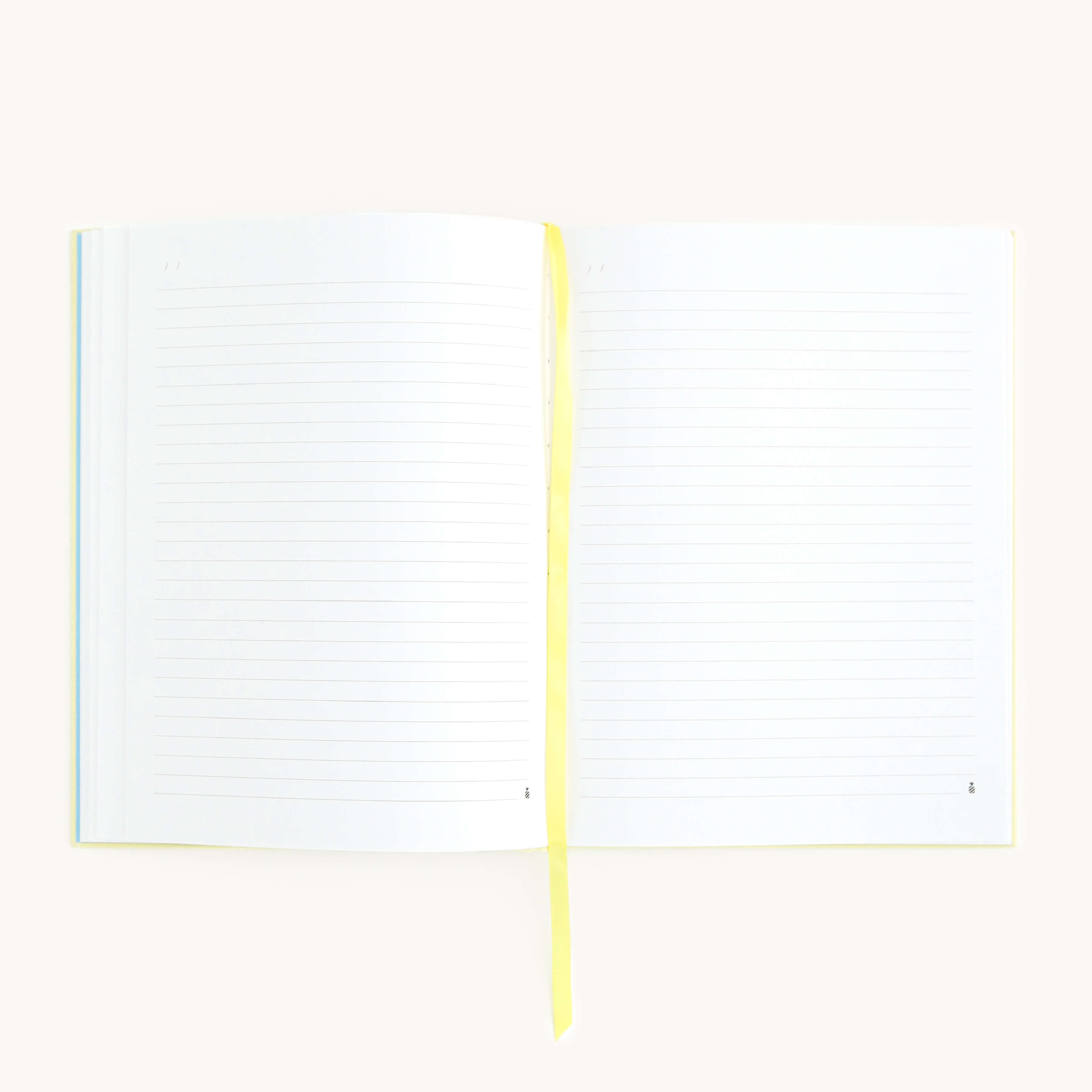 A Linen Journal - Yellow by Simplified, with lined pages and a yellow ribbon bookmark, rests open in the center. Its laid flat on a plain white background, inviting creativity and reflection.