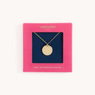 The Necklace - Grace Not Perfection by Simplified features a gold piece with a round pendant inscribed GRACE, NOT PERFECTION, exuding elegance. It’s presented in a pink SIMPLIFIED box that captures simplicity, bearing the inscription GRACE, NOT PERFECTION NECKLACE at the bottom.