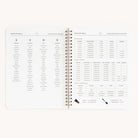 The Simplified Workbook - Meal Planning is an open spiral-bound planner showcasing meal lists, kitchen measurements, and conversions. The left page highlights foods and utensils for grocery shopping; the right includes detailed tables for measuring dry and liquid ingredients.