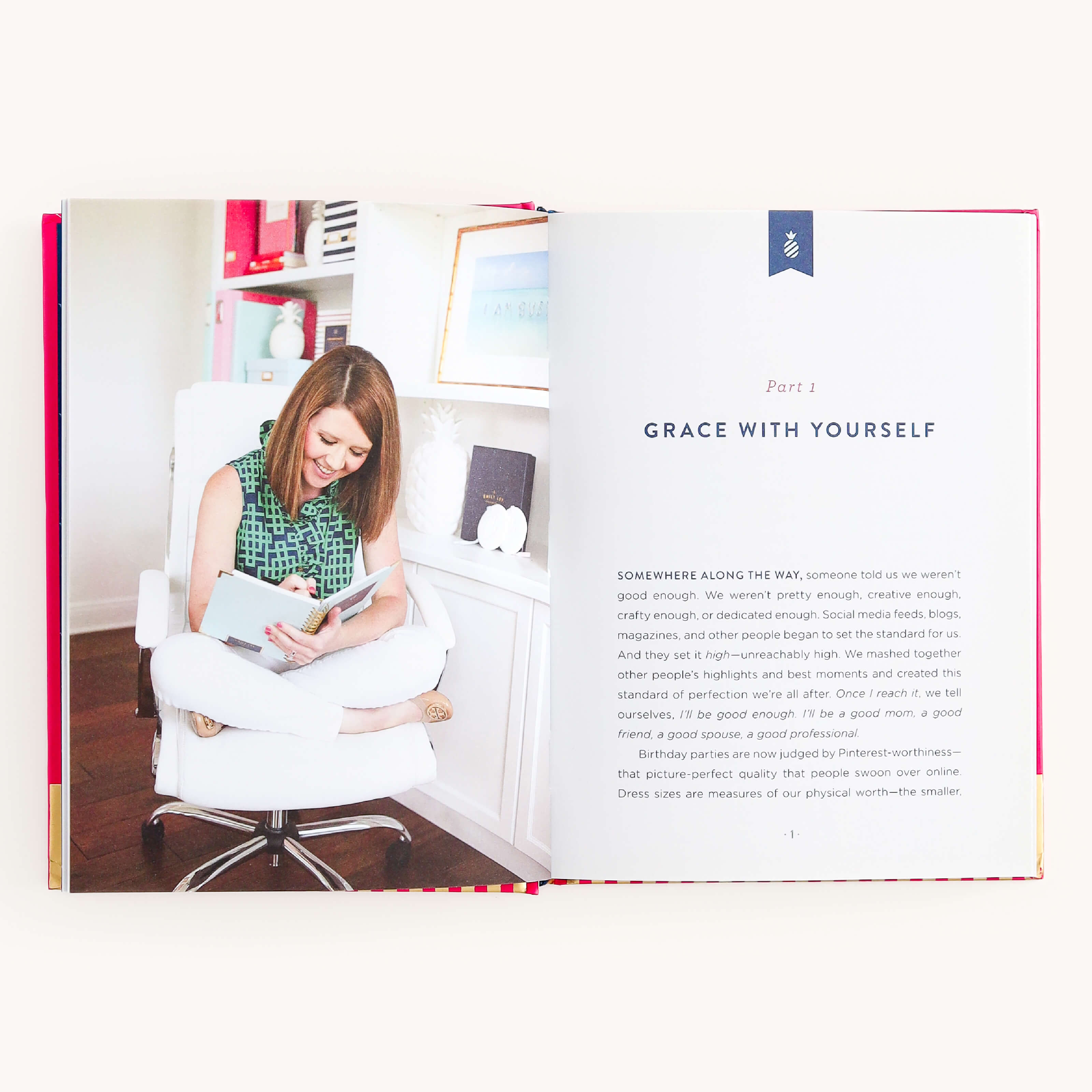 An open book from the brand Simplified featuring Grace Not Perfection by Emily Ley. The left page shows a woman smiling in a white chair, writing in a notepad. The right page reads Part 1: Grace with Yourself, inviting readers to embrace imperfection for fulfillment.