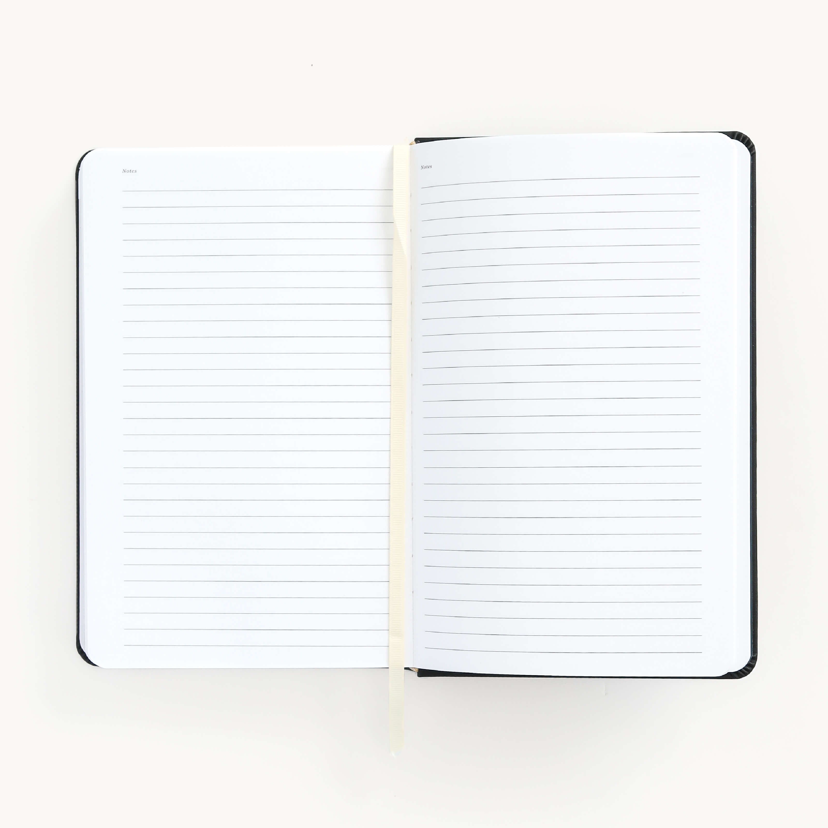 2025 Daily Dapperdesk Planner in the Black Tie leatherette cover open to the notes pages. Features a two-page spread with blank lined notes pages and ivory grosgrain ribbon page marker. 