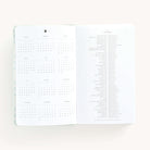 2025 Daily Dapperdesk Planner by Emily Ley in the Sea Salt leatherette cover open to the yearly calendar overview and holidays list. Features a two-page spread with a full 12-month calendar view on the left and important U.S. holidays on the right. 