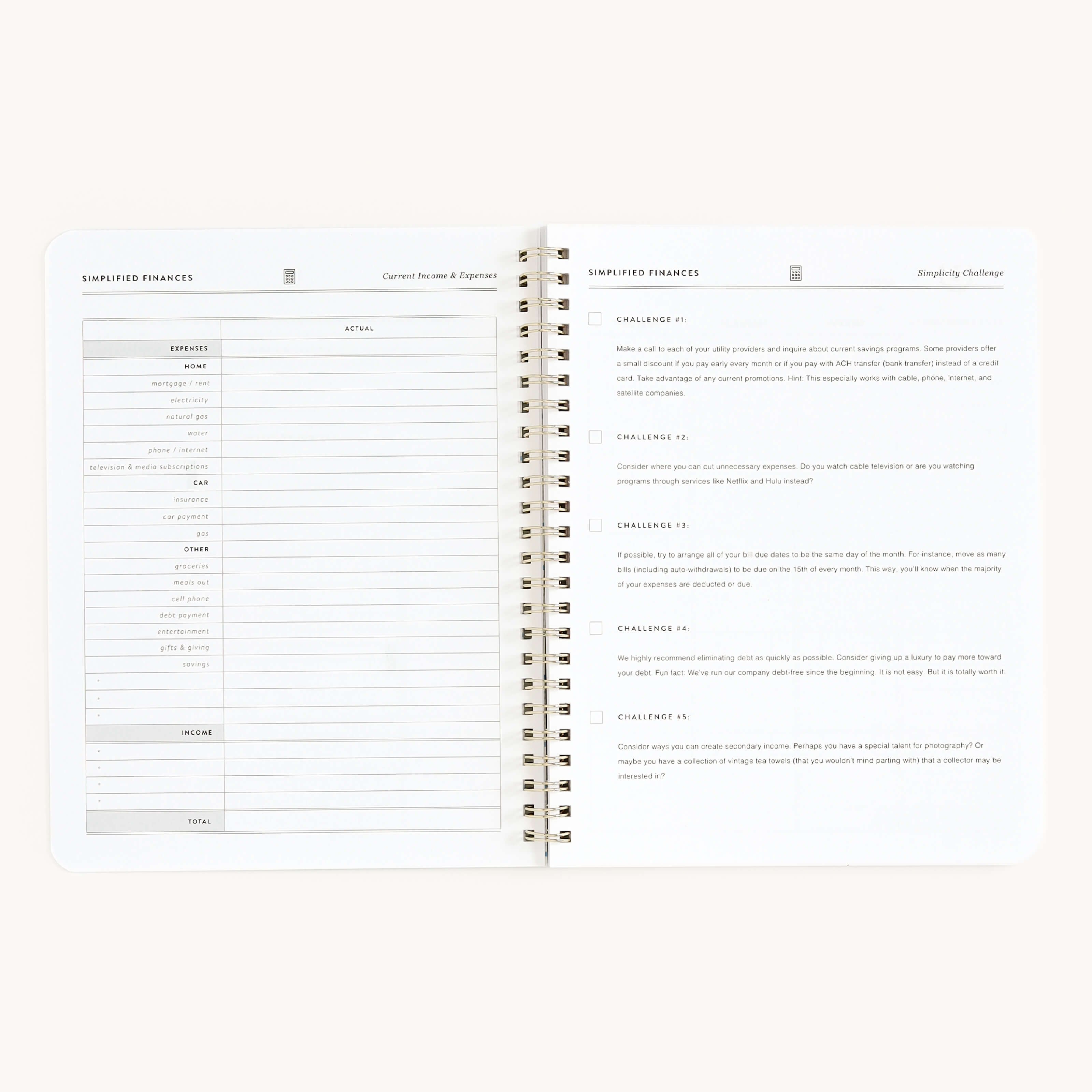 The Simplified Finances workbook by Simplified features an open spiral-bound design with a budget table on the left page for tracking income and expenses. The right page includes a Simplifying Challenge with checkboxes for tasks 1 to 5, ideal for managing finances.