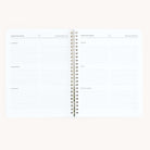 The Workbook - Travel Planning by Simplified is a spiral-bound notebook with white lined pages and black text, featuring sections for clothing, accessories, toiletries, health, tech, and misc. Its perfect for organizing your packing list and travel plans.