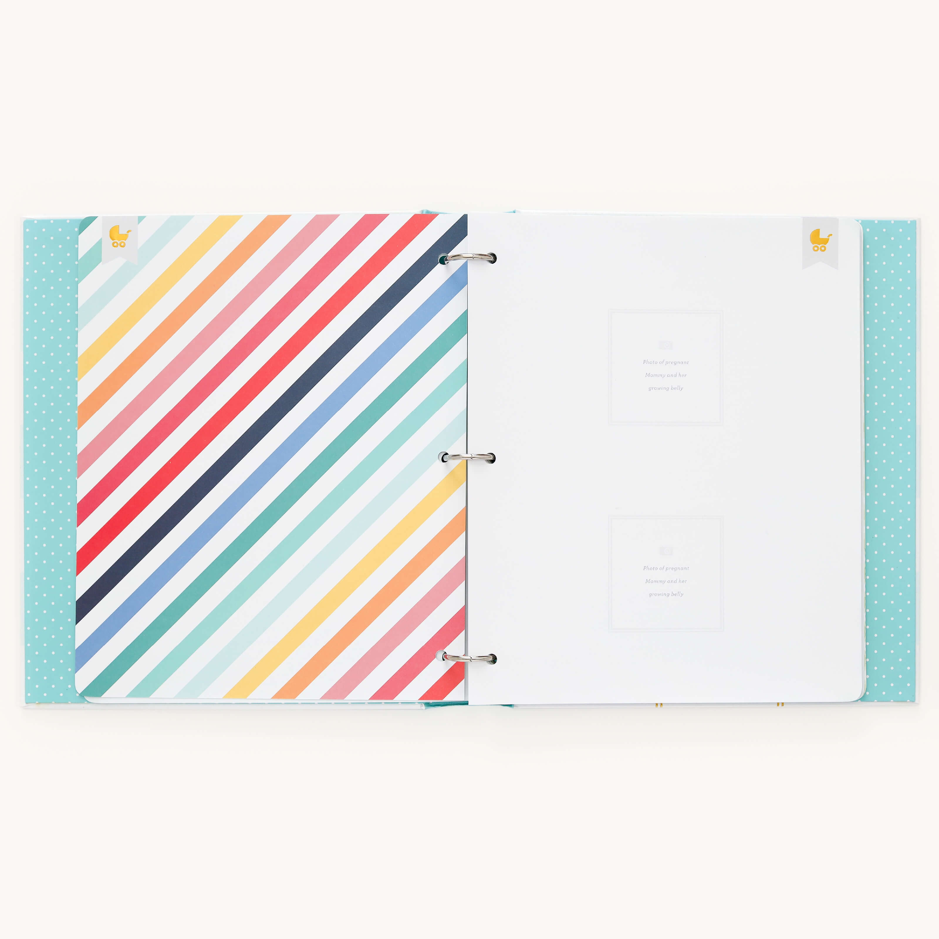 The Simplified Baby Book - Mint features a blue cover with white polka dots, an open binder with blank guided writing pages on the right, and a colorful diagonal striped divider on the left, perfect for creating a personalized experience like a baby book.