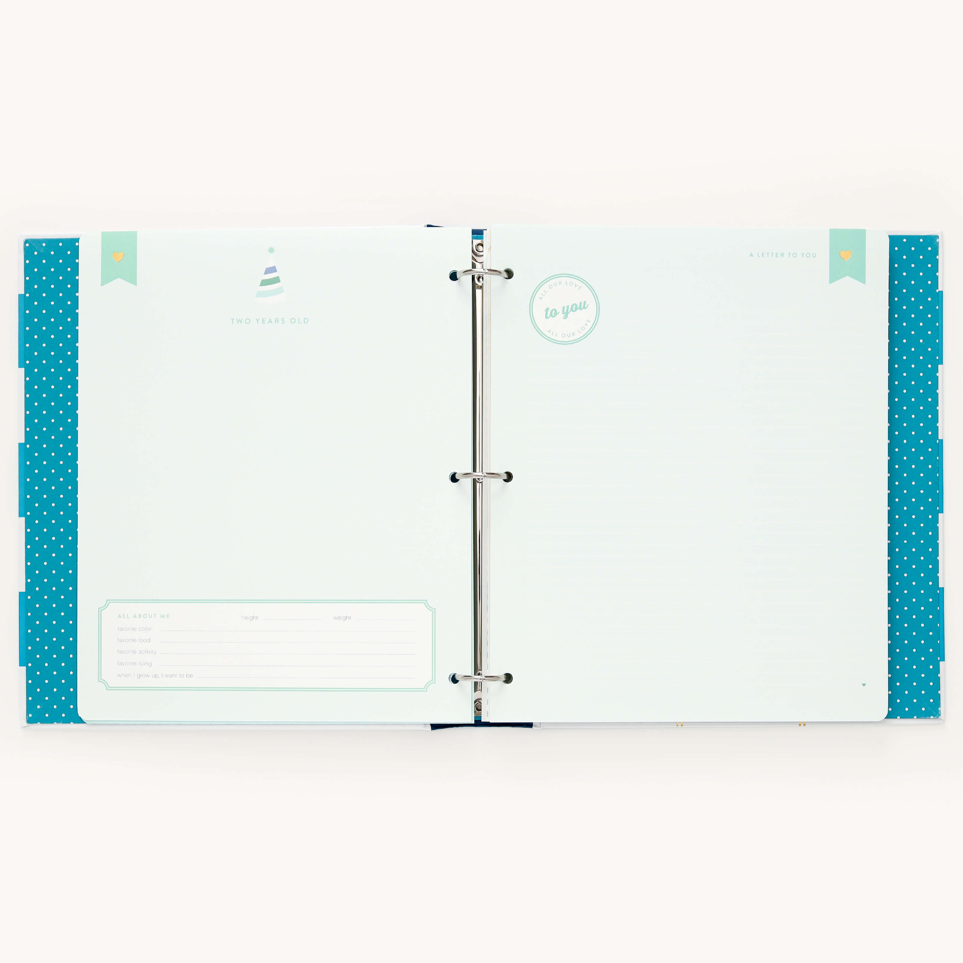 The Simplified Big Kid Book - Teal is an open scrapbook with a three-ring binder, featuring a memorable teal design. It includes pages with polka dot edges and a party hat icon for sections celebrating Two Years Old, perfect for capturing moments of child growth.