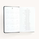 2025 Daily Dapperdesk Planner by Emily Ley in the Black Tie leatherette cover open to the yearly calendar overview and holidays list. Features a two-page spread with a full 12-month calendar view on the left and important U.S. holidays on the right. 