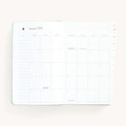 Monthly spread in the 2025 Daily Dapperdesk Planner in the Sea Salt leatherette cover featuring mylar tabs with gold foil details.