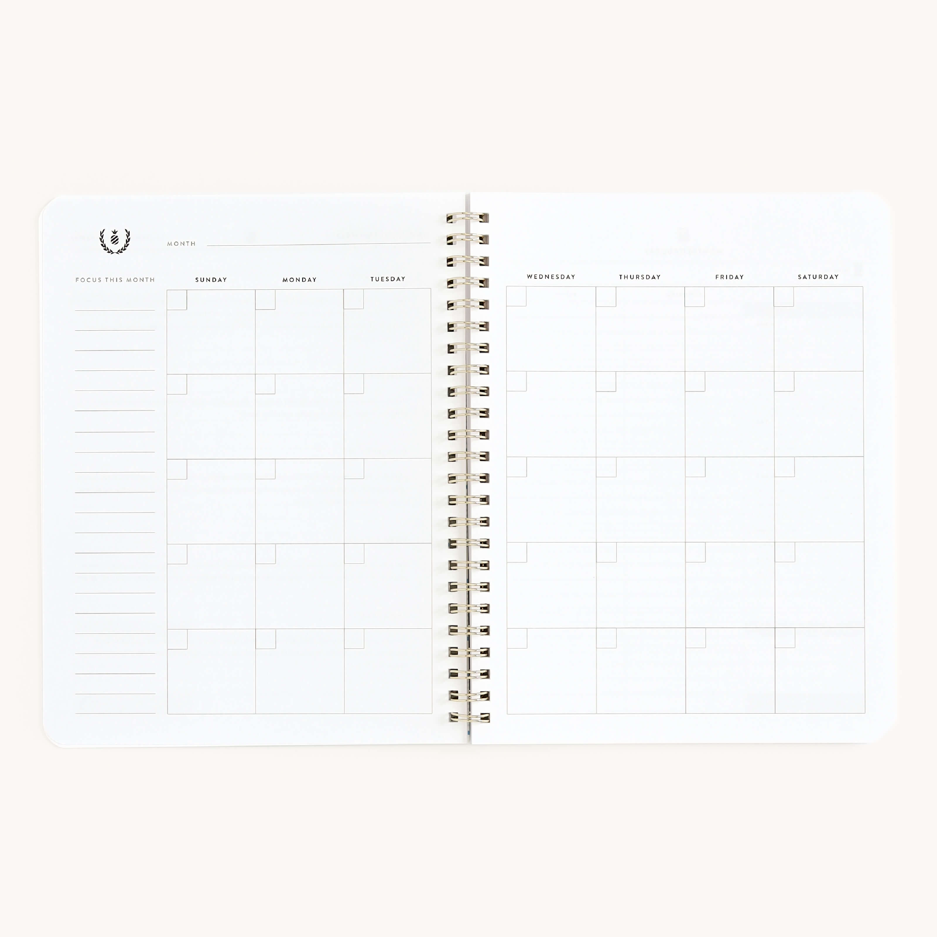 The Simplified Workbook - Finances is an open spiral-bound planner featuring a blank monthly calendar layout with Sunday to Saturday columns, perfect for tracking financial goals. A decorative emblem adorns the top left on a crisp white background.