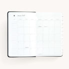 Monthly spread in the 2025 Daily Dapperdesk Planner in the Black Tie leatherette cover featuring mylar tabs with gold foil details.