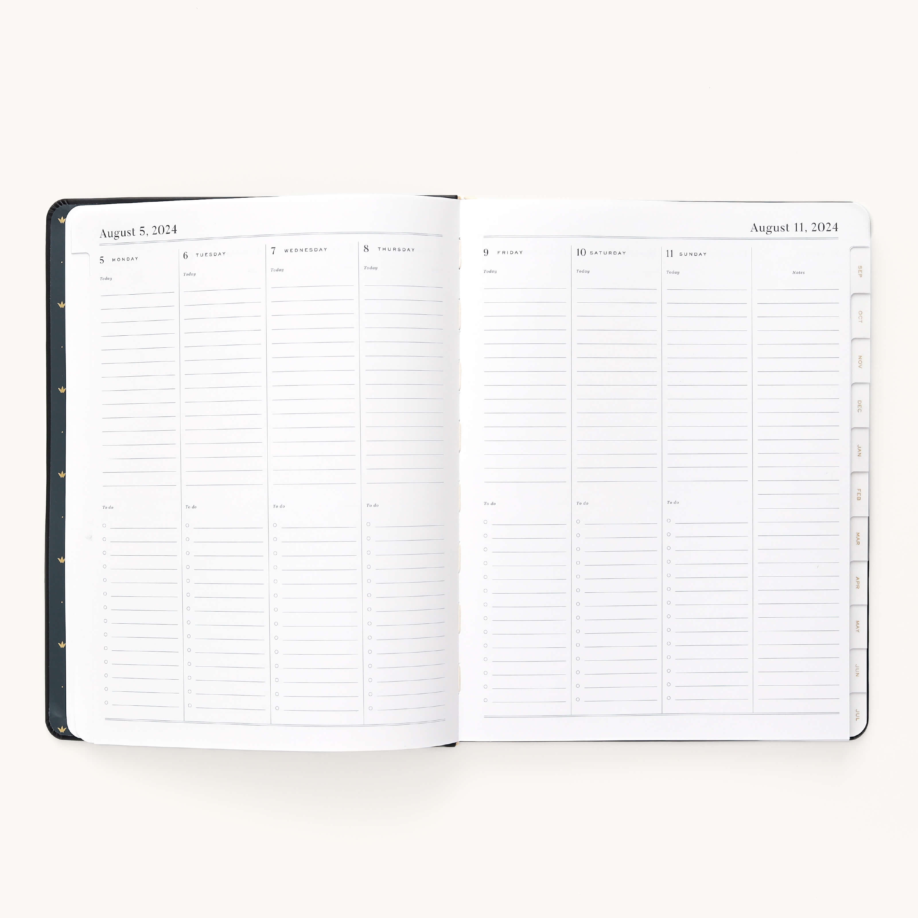 The Simplified 2024-2025 Weekly Dapperdesk Planner - Black Tie features a weekly layout from August 5 to August 11, 2024. It has high-quality paper with daily columns, lined sections for notes and activities, a black leatherette cover with round metal rings, and visible tabs on the right.