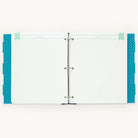 The open binder features Simplifieds Teal Big Kid Books two metal rings securing white lined pages. It includes blue polka-dotted tab dividers and labeled tabs with page headings to track a childs growth milestones.