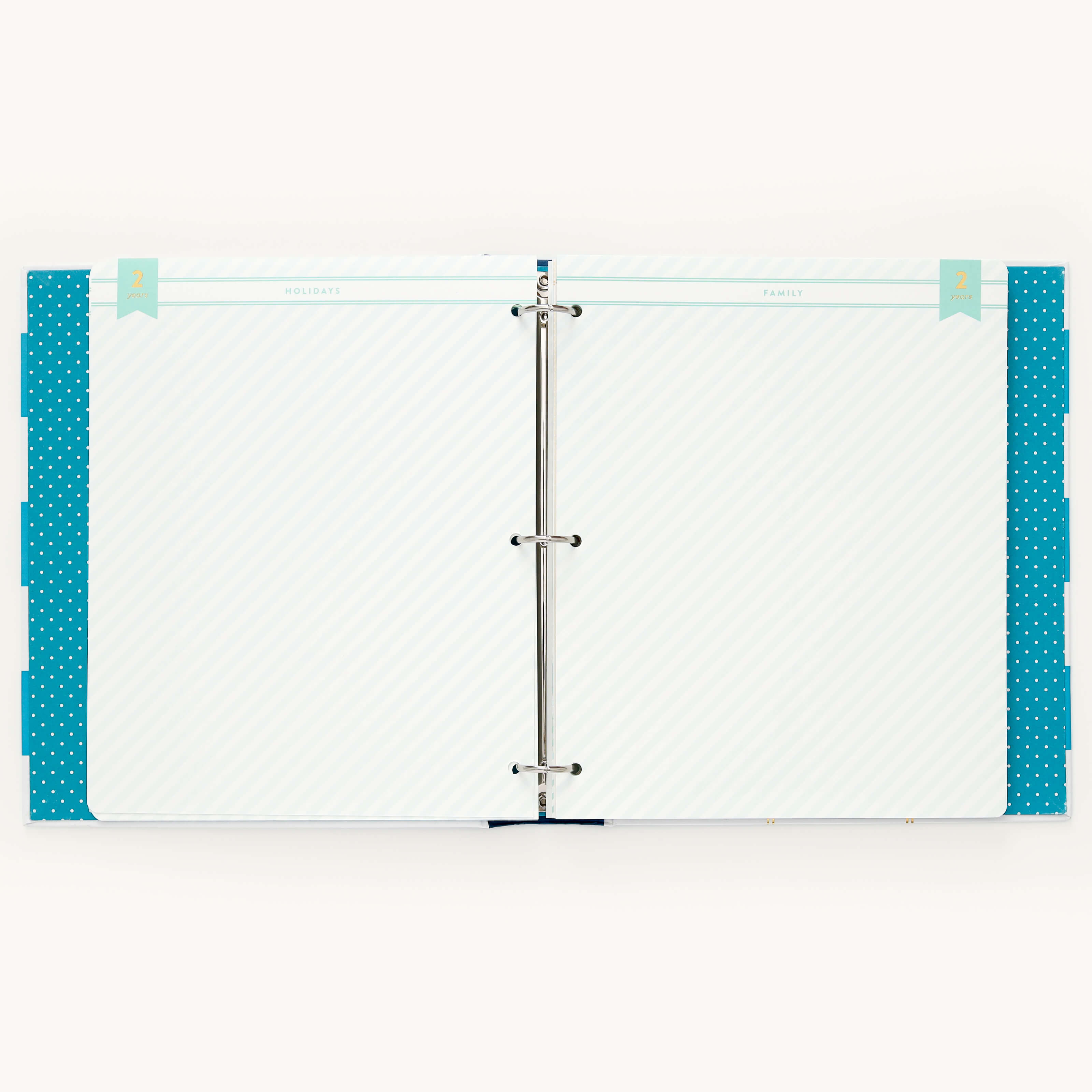 The open binder features Simplifieds Teal Big Kid Books two metal rings securing white lined pages. It includes blue polka-dotted tab dividers and labeled tabs with page headings to track a childs growth milestones.