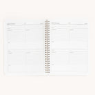 The Workbook - Meal Planning by Simplified is an open spiral-bound notebook showing two pages titled Simplified Meals. It features sections for ingredients, directions, and notes with a clean, minimalist design ideal for organizing grocery shopping and ensuring ample writing space.