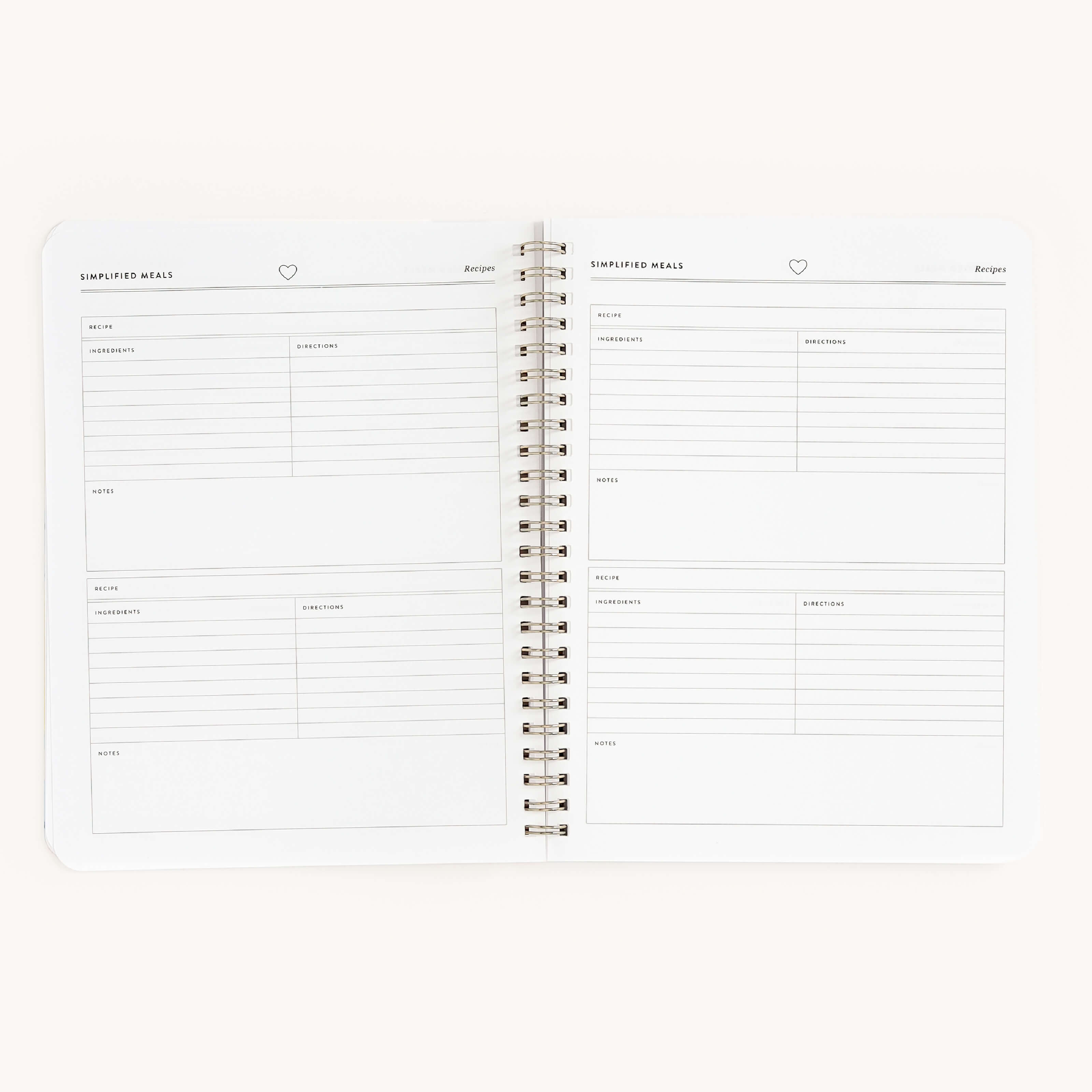 The Workbook - Meal Planning by Simplified is an open spiral-bound notebook showing two pages titled Simplified Meals. It features sections for ingredients, directions, and notes with a clean, minimalist design ideal for organizing grocery shopping and ensuring ample writing space.